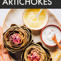 Plate of freshly cooked artichokes with vegan dipping sauces on the side