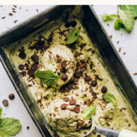 Ice cream scoop in a loaf pan filled with our vegan no-churn mint chocolate chip ice cream