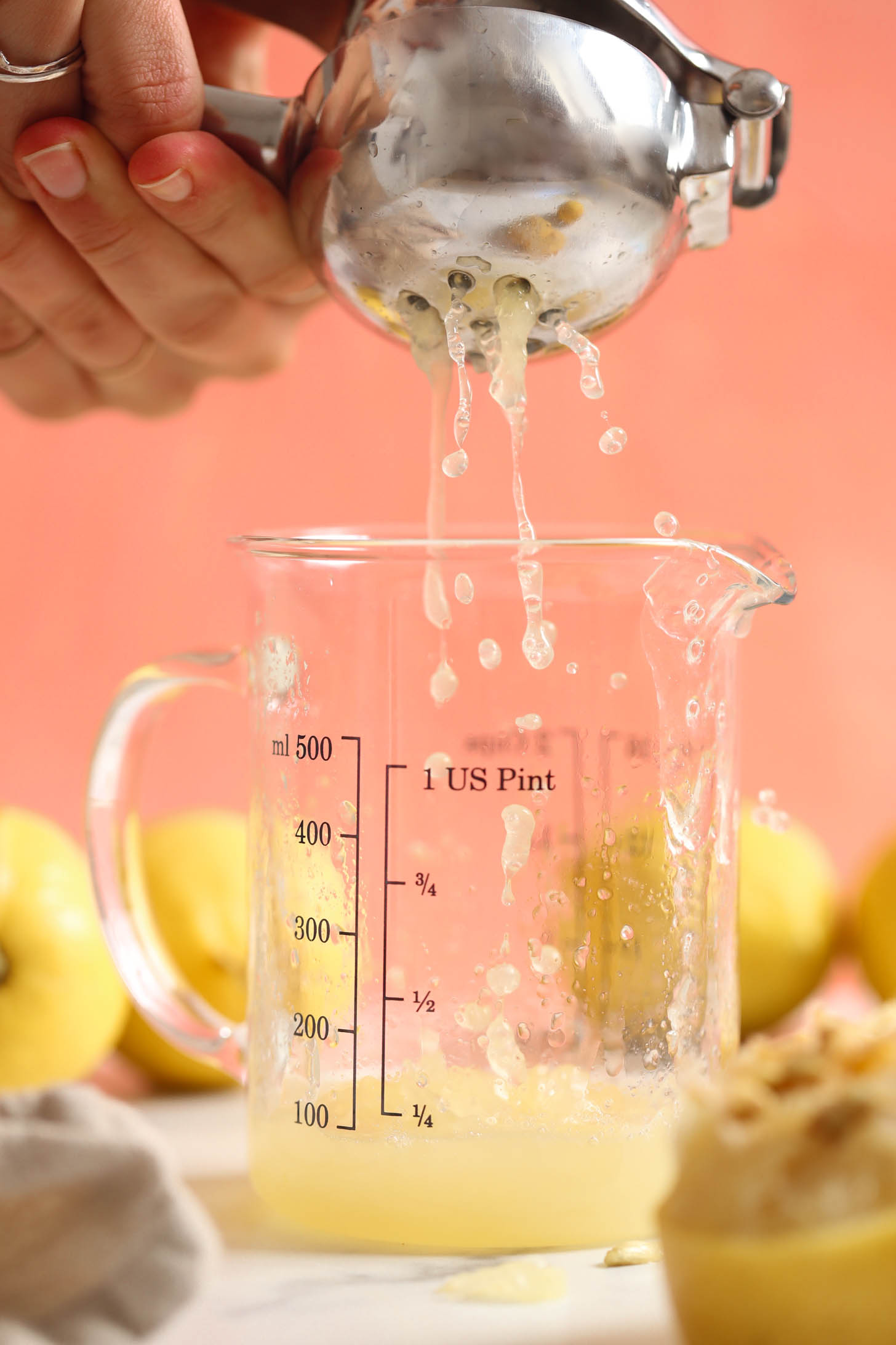 Using a citrus juicer to squeeze a lemon into a measuring glass