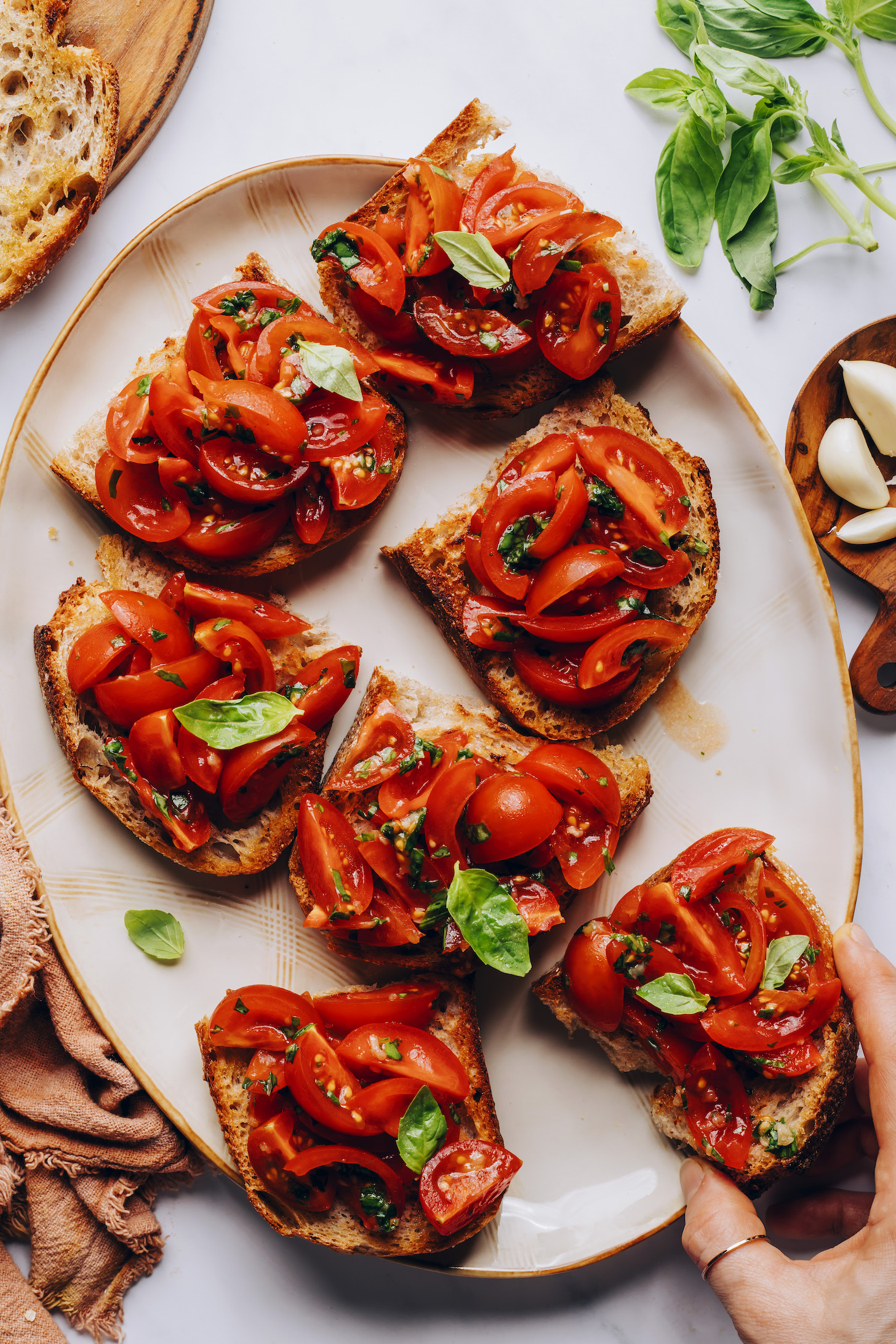 Picking up a slice of cherry tomato basil bruschetta from a plate