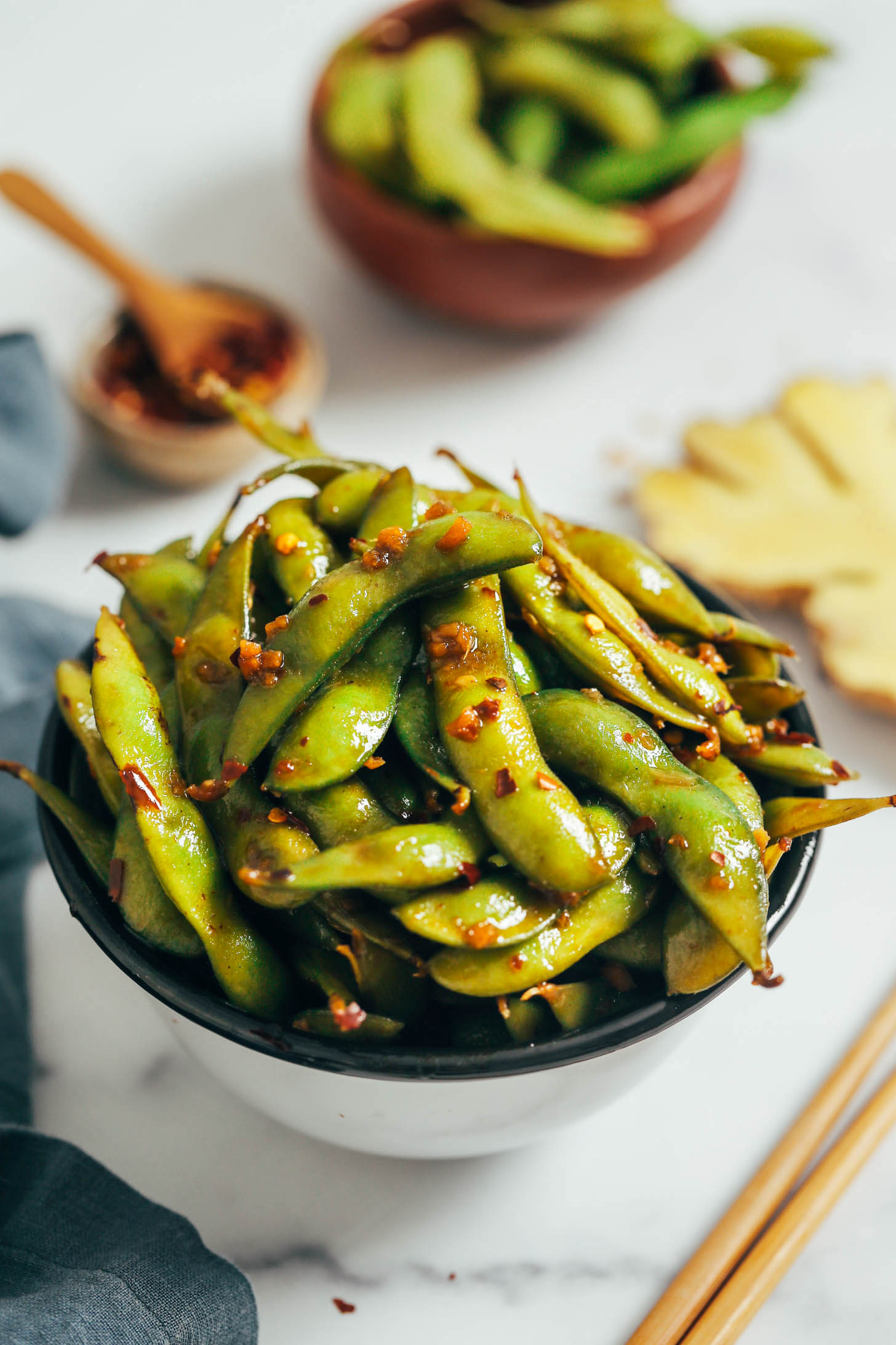 Overflowing bowl of spicy chili garlic edamame in pods