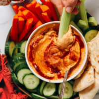 Dipping a celery stick into a bowl of our spicy chipotle hummus recipe