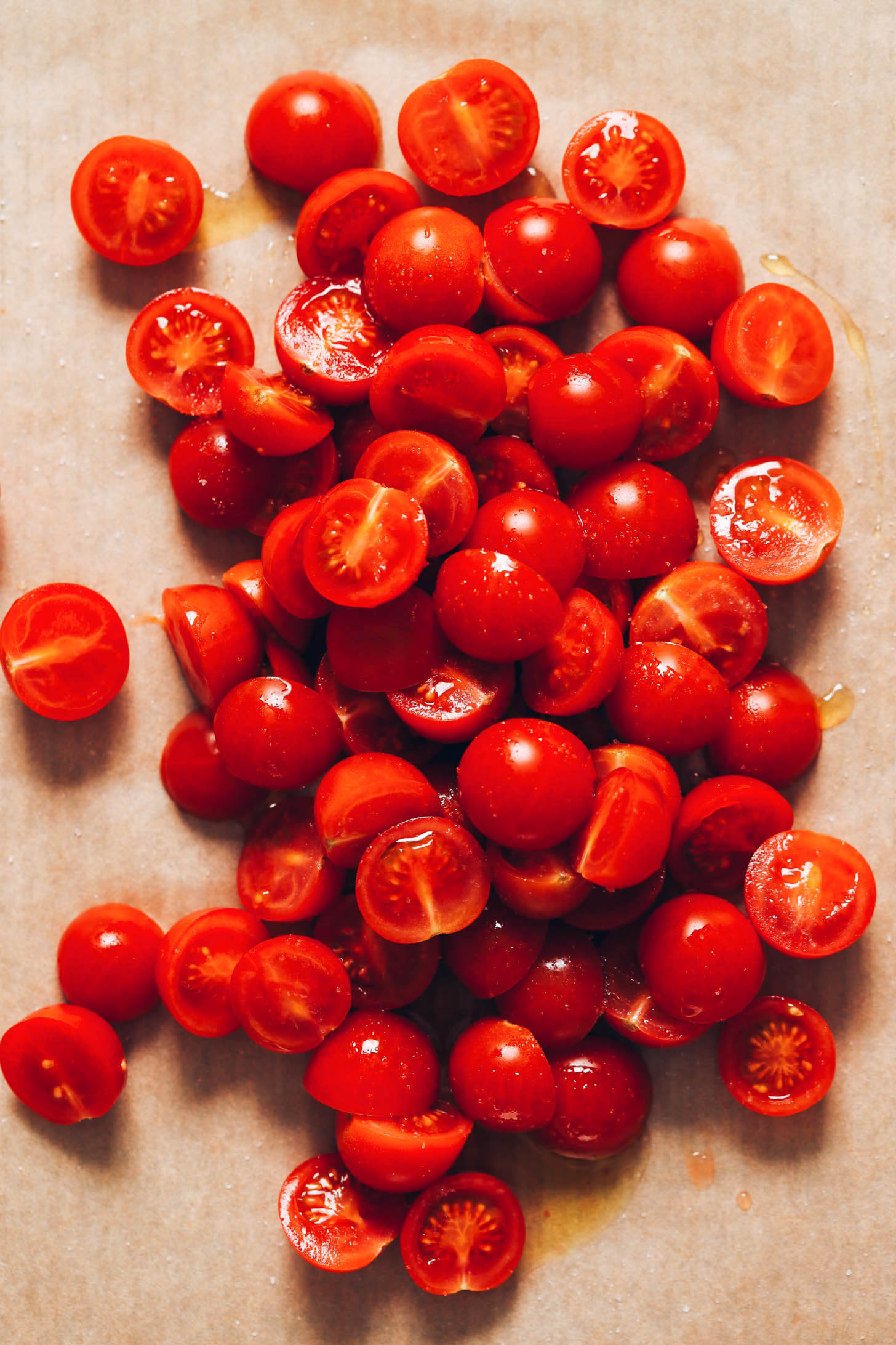 Halved cherry tomatoes on a parchment-lined baking sheet
