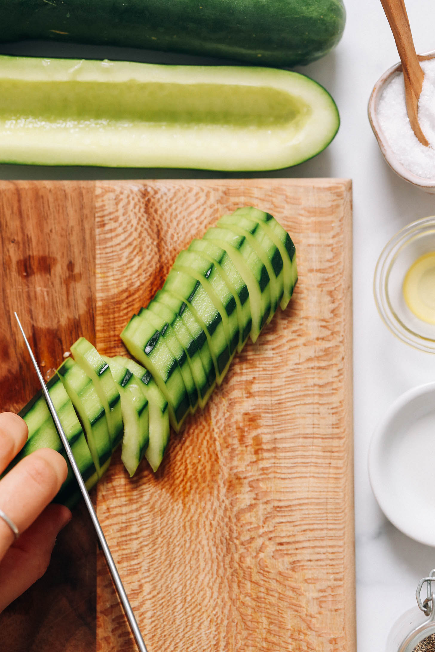Using a sharp knife to slice a cucumber on a cutting board