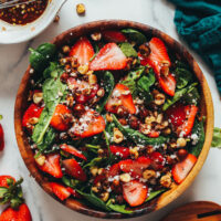 Wood serving bowl filled with strawberry spinach salad with dairy-free feta crumbles