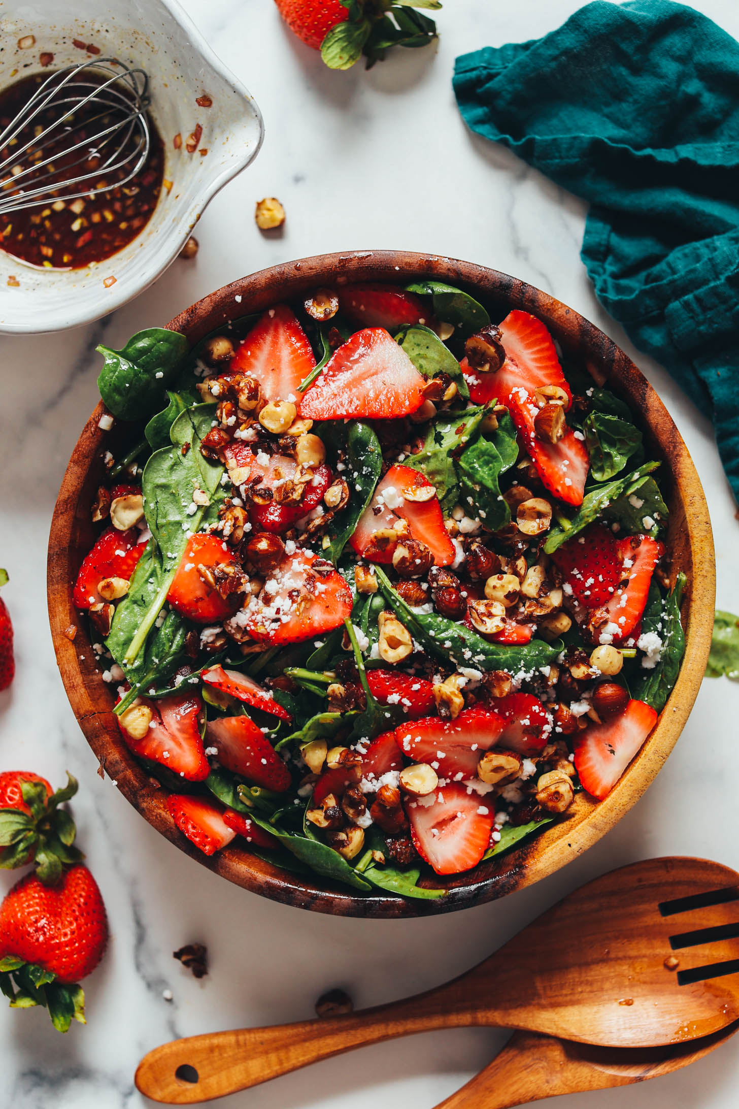 Overhead shot of a gorgeous strawberry spinach salad with candied hazelnuts and dairy-free feta crumbles