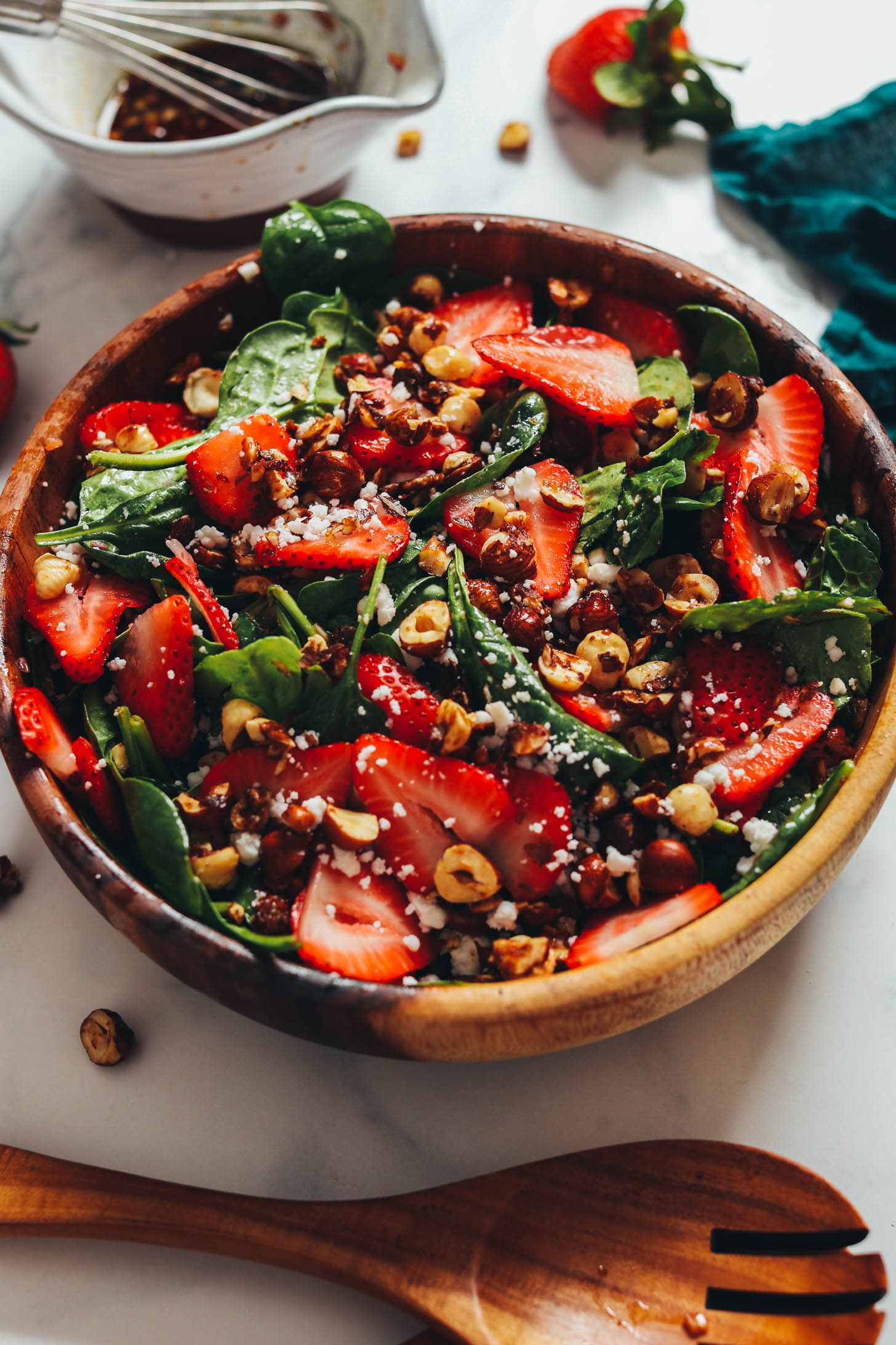 Angled shot of a wood serving bowl filled with strawberry spinach salad