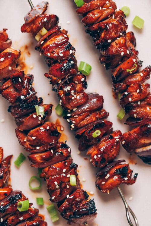 Close up shot of grilled chicken skewers topped with a teriyaki glaze