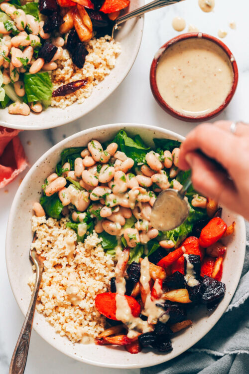 Drizzling vegan caesar dressing over a nourish bowl