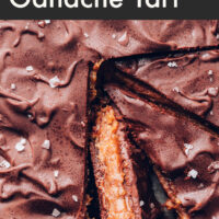 A vegan and gluten-free salted caramel chocolate ganache tart with a slice cut out