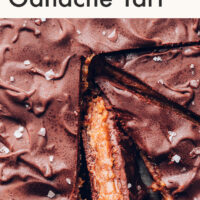 A vegan and gluten-free salted caramel chocolate ganache tart with a slice cut out