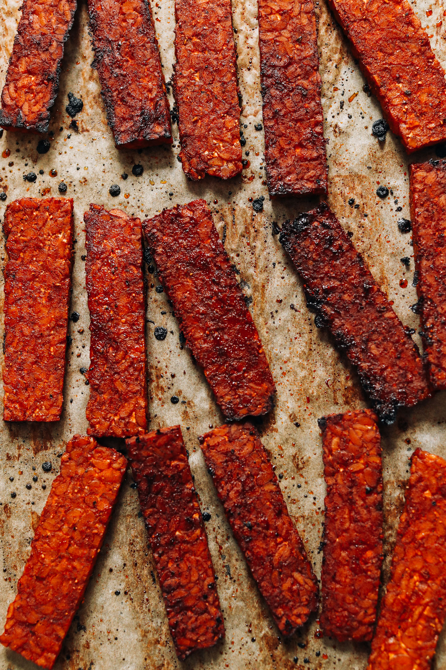 Slices of tempeh bacon on a baking sheet