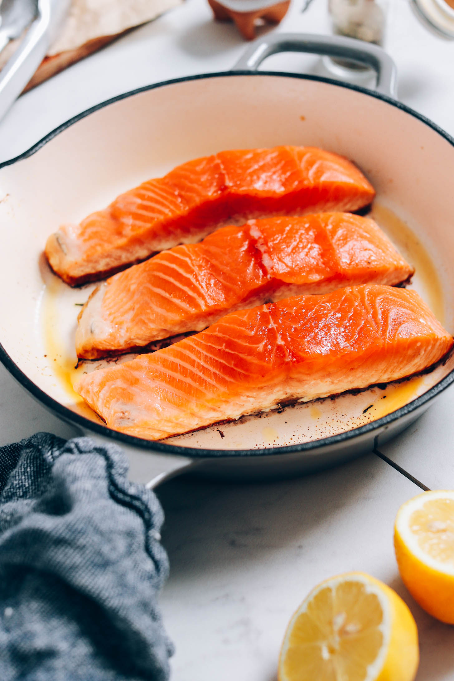 Partially cooked salmon filets in an enameled cast iron skillet