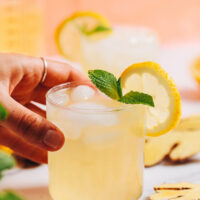 Hand holding a glass of homemade ginger lemonade