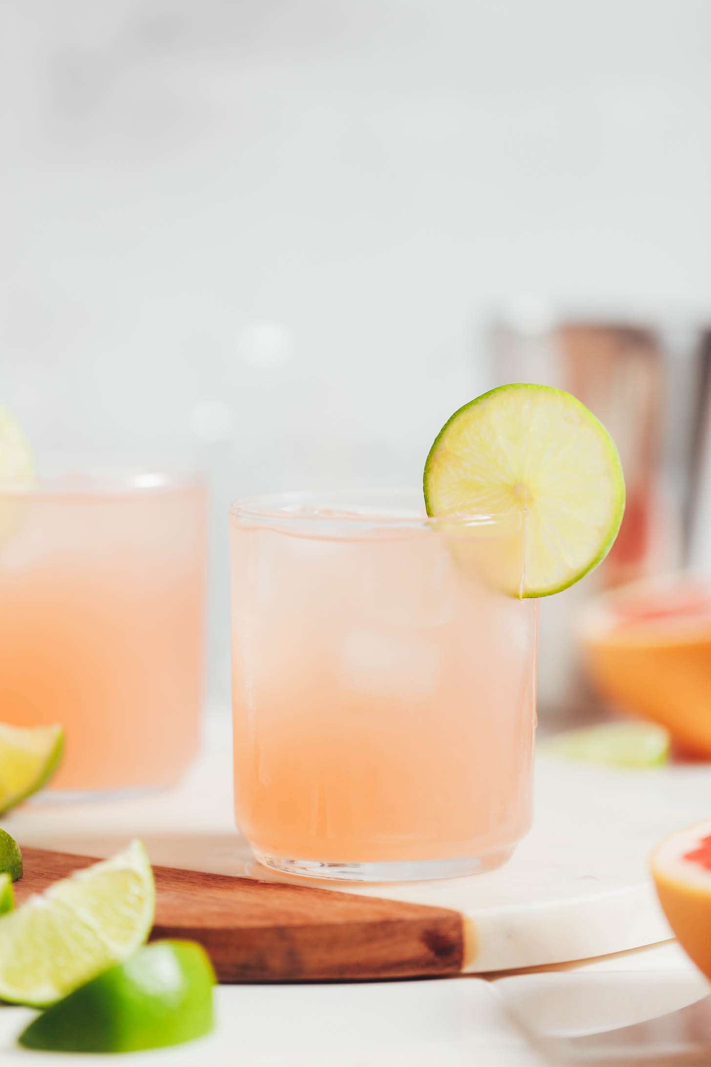 Glasses of grapefruit lime spritzers on a ceramic and wood cutting board