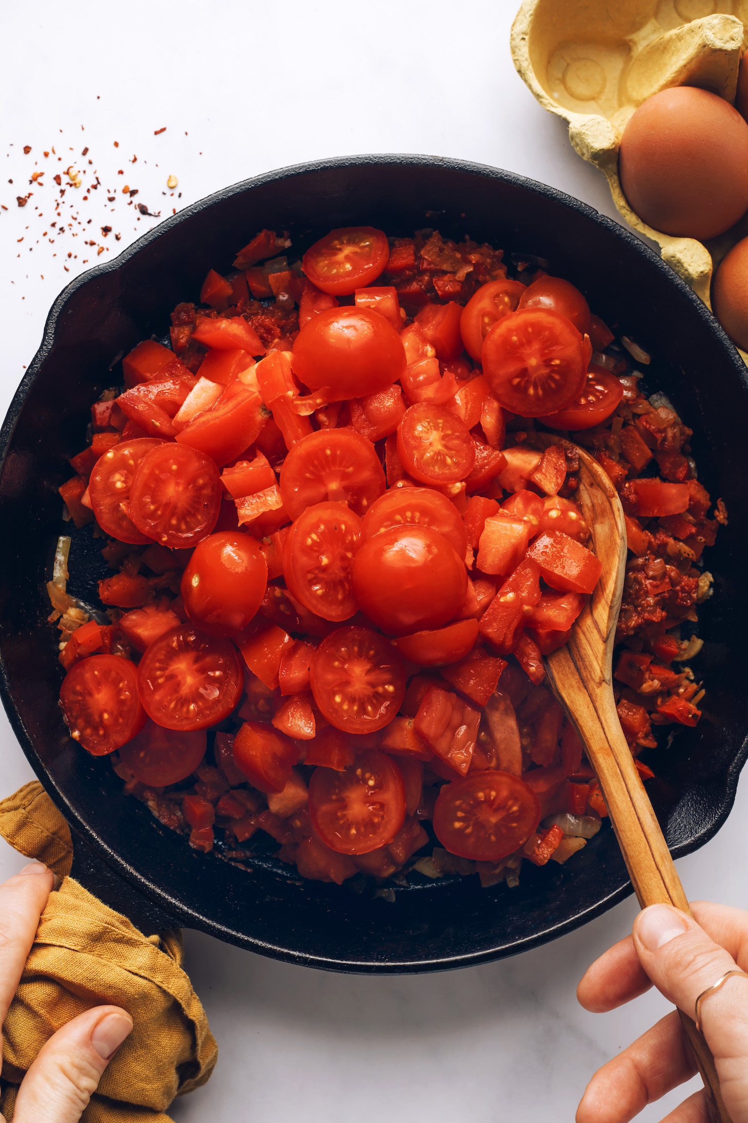 Bir tavada çeri domatesleri ve doğranmış domatesleri karıştırarak