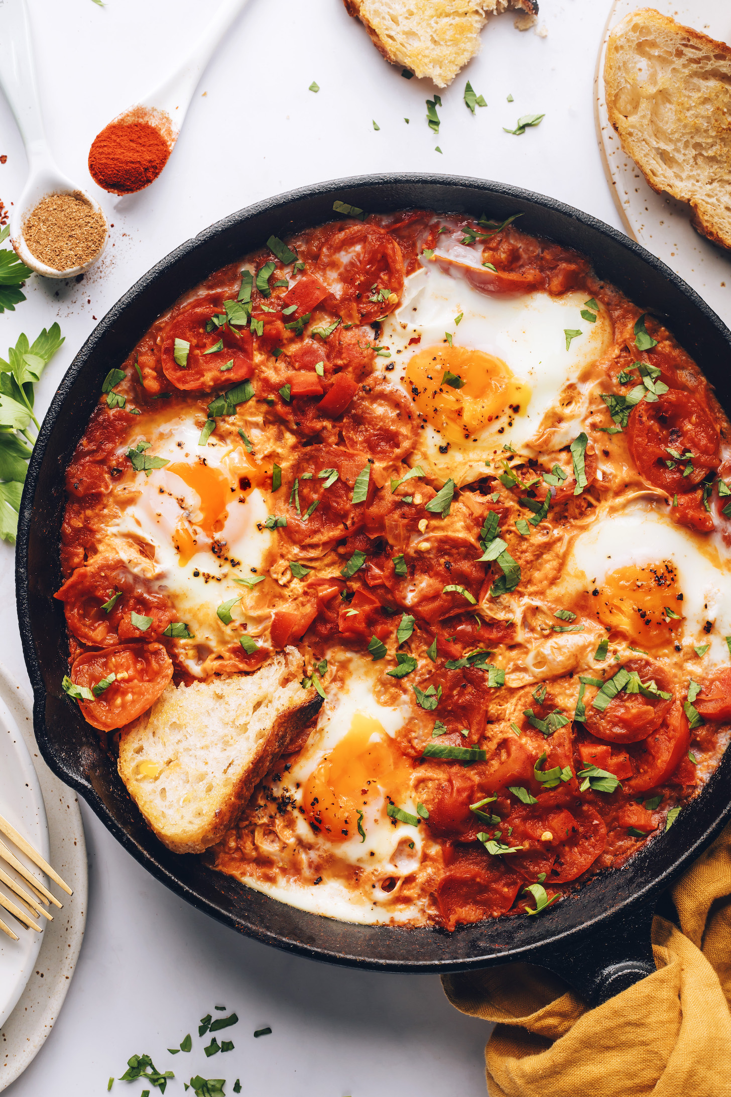 Toasted bread next to and in a skillet of shakshuka