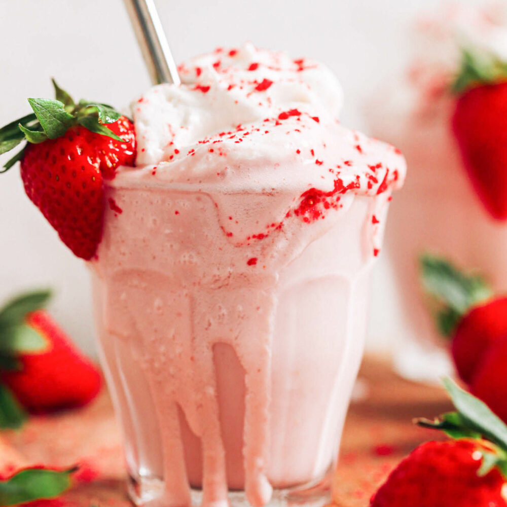 Close up shot of an overflowing vegan strawberry milkshake