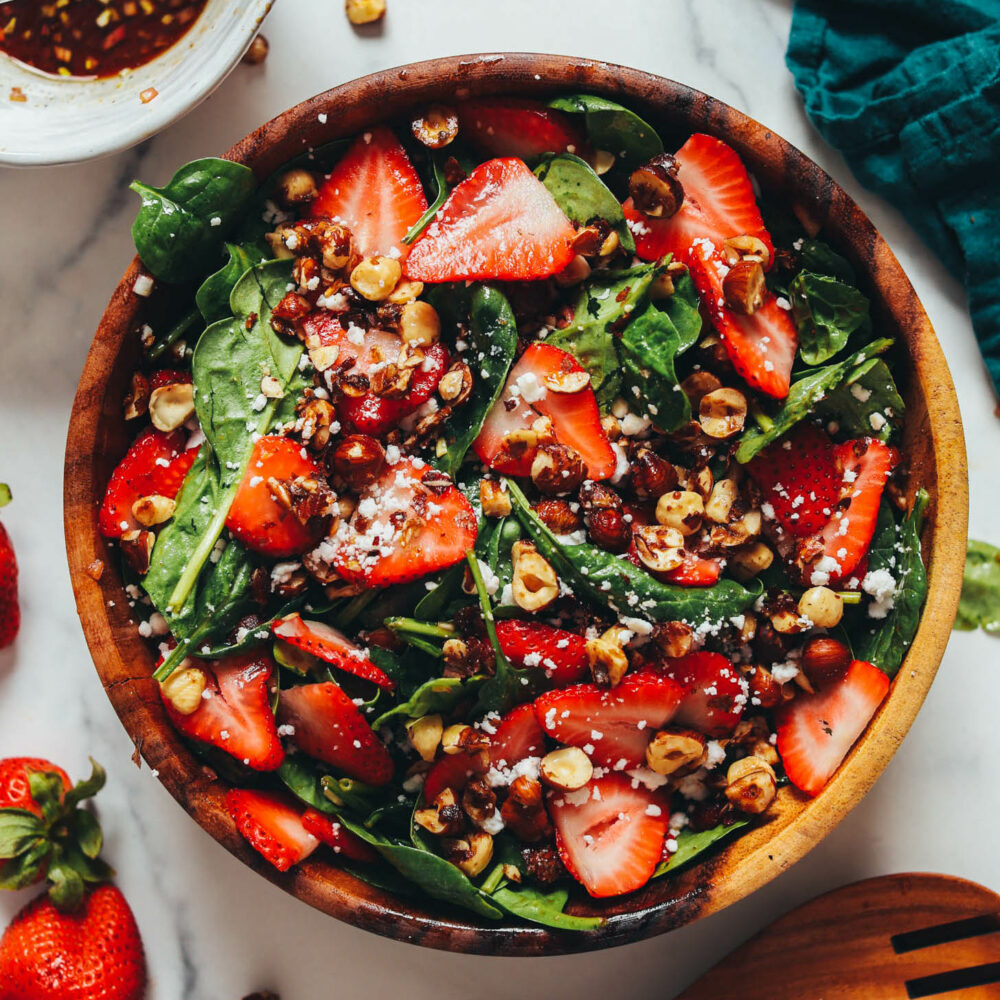 Overhead shot of a wooden serving bowl filled with a strawberry spinach salad