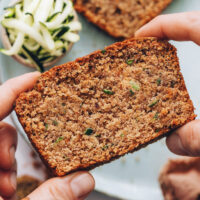 Holding up a slice of gluten-free zucchini bread to show the crumb texture