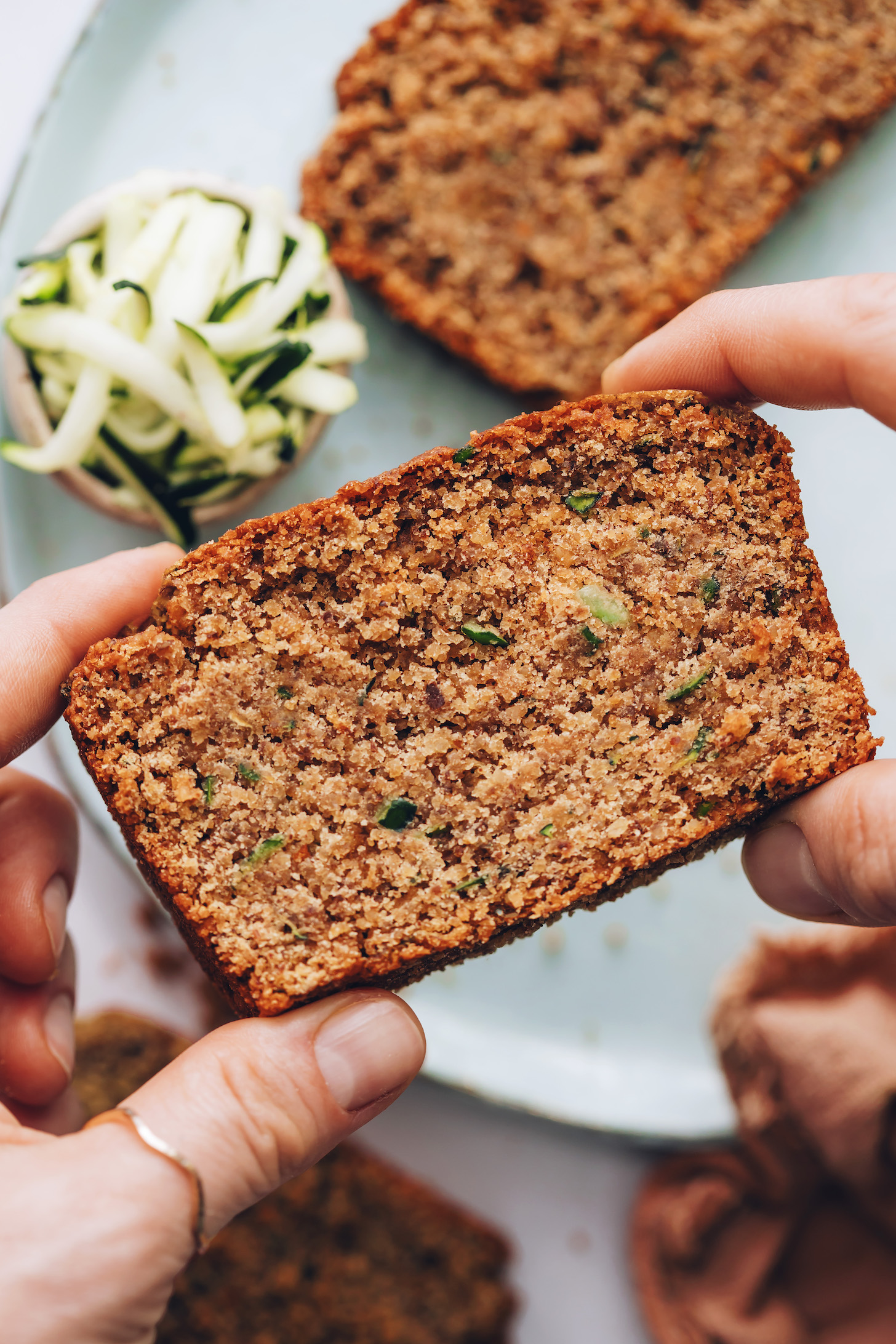 Holding up a slice of vegan gluten-free zucchini bread to show the texture