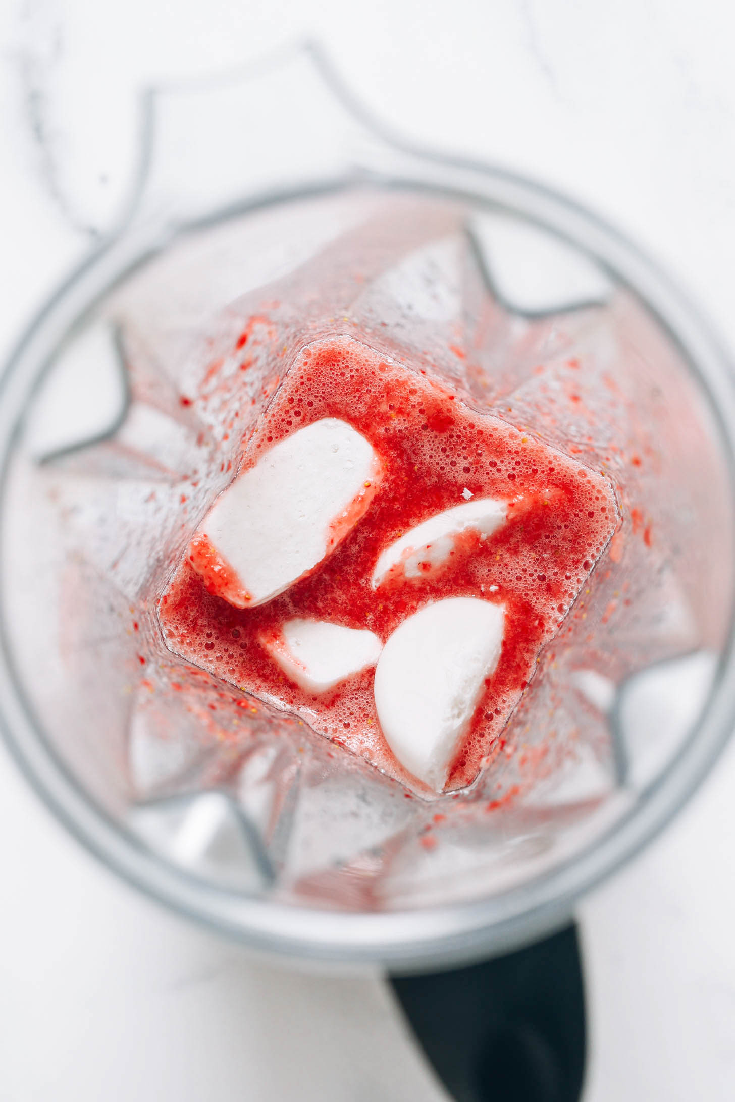 Des glaçons au lait de coco dans un mixeur pour montrer comment faire un milk-shake aux fraises sans glace