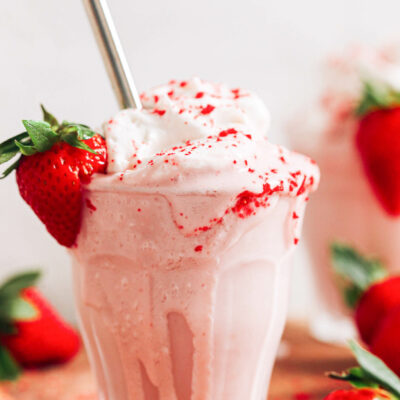 Metal straw in an overflowing glass with our strawberry milkshake recipe