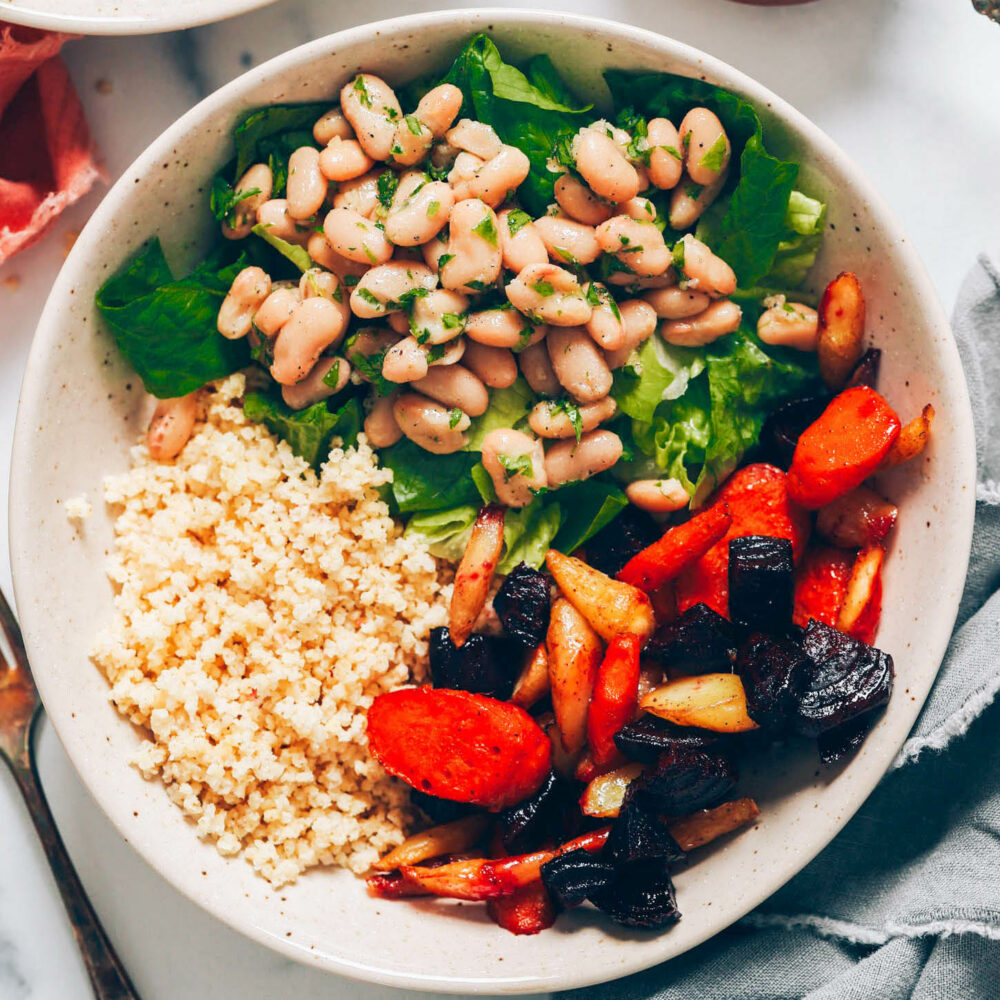 Bowl with roasted carrots and beets, lettuce, millet, and white beans