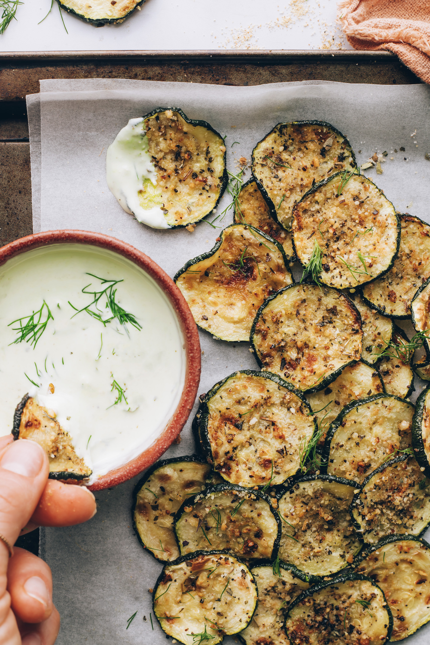 Dipping a caramelized zucchini slice into a bowl of ranch