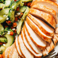 Plate with sliced baked chicken breast and cucumber salad