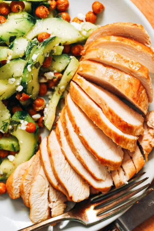 Plate with sliced baked chicken breast and cucumber salad