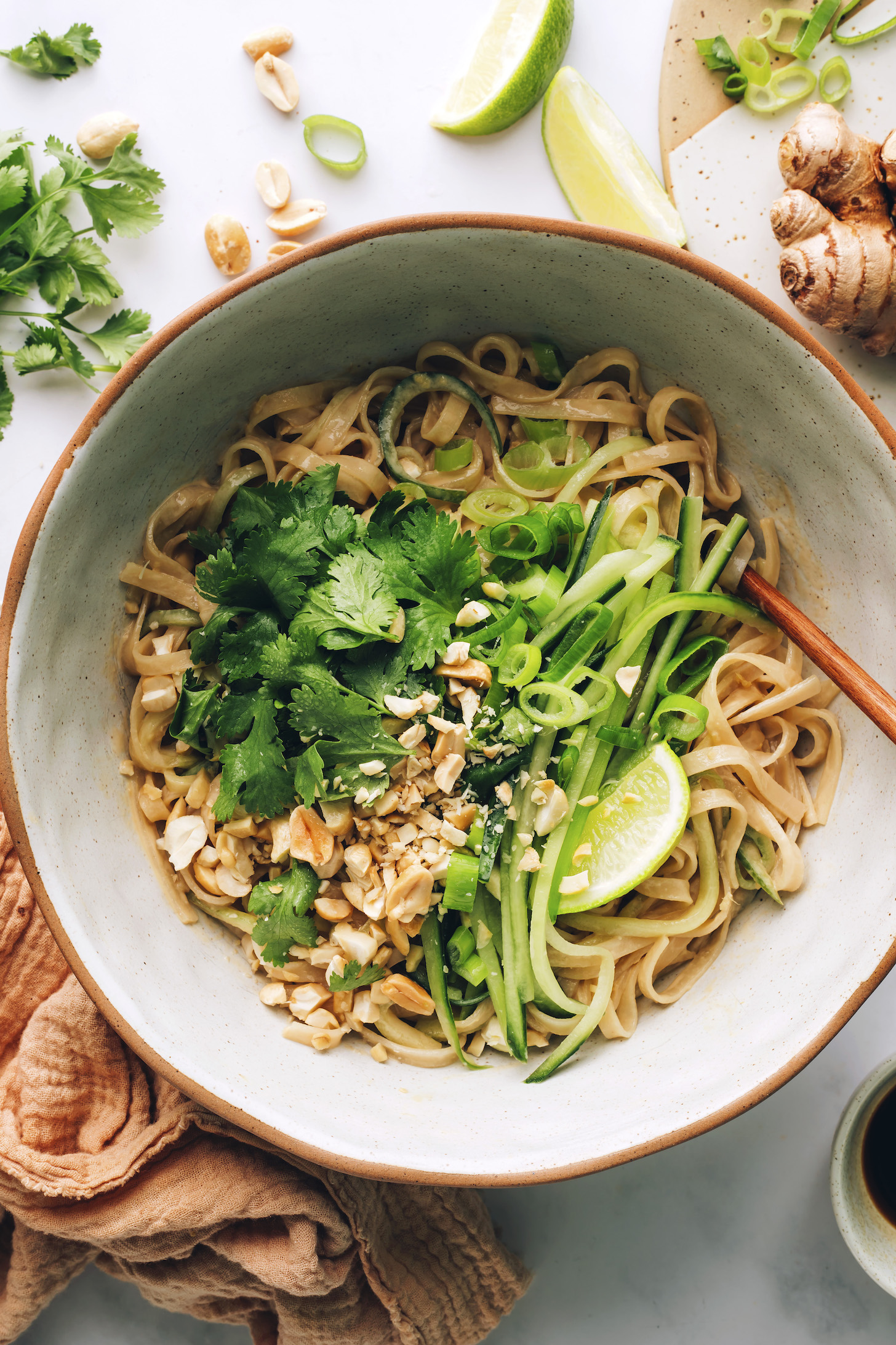 Cucumbers, lime, peanuts, and cilantro over a bowl of saucy noodles