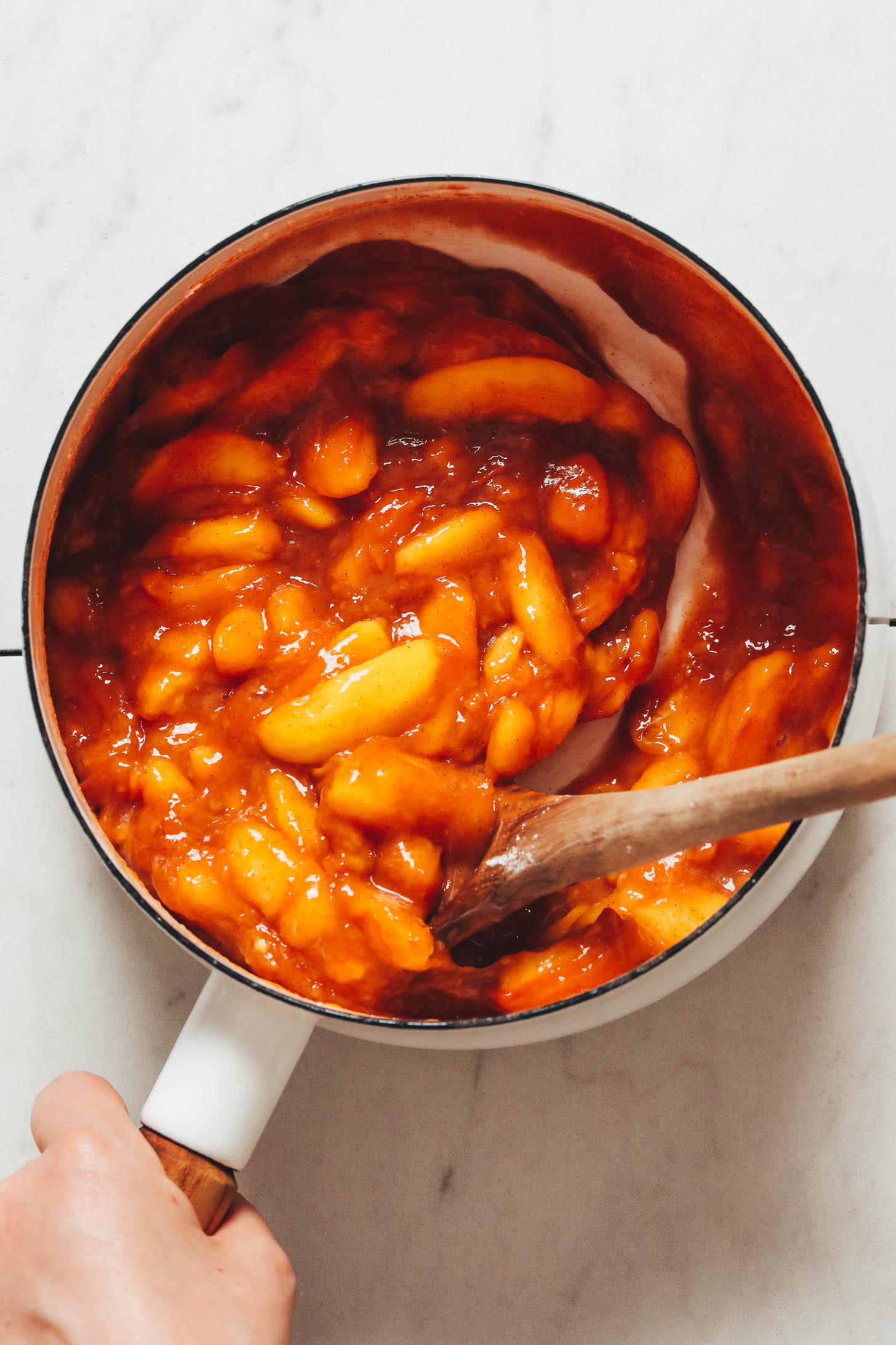 Saucy cinnamon-infused peaches in a white saucepan