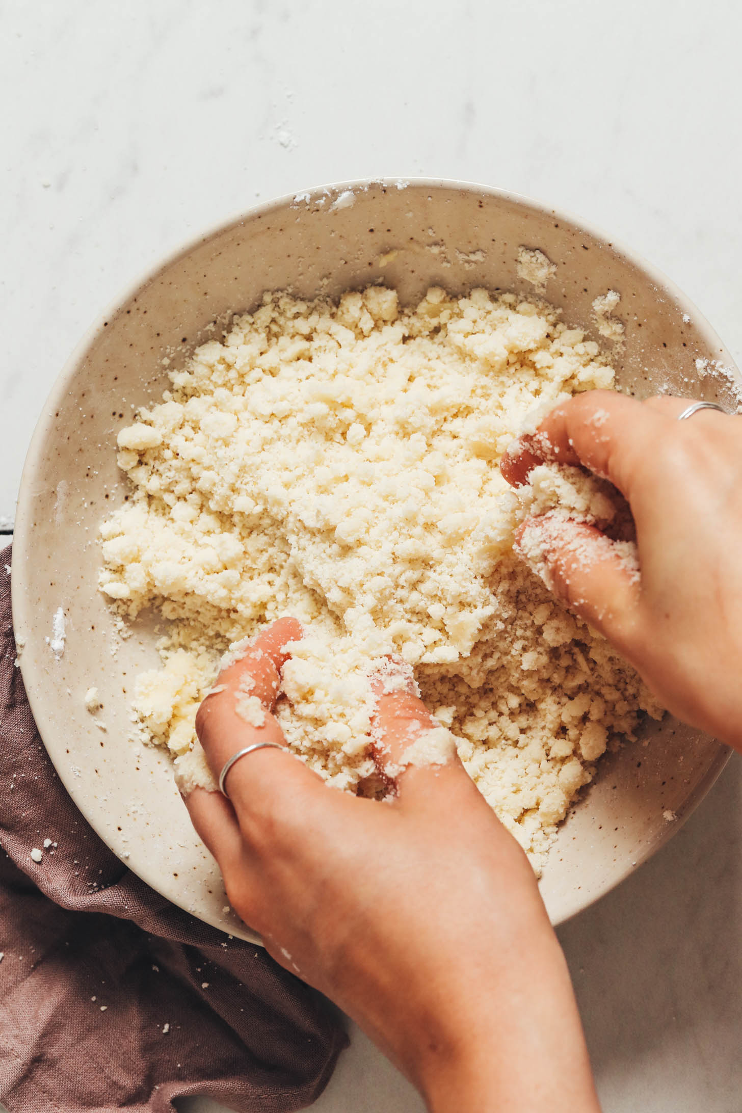 Hands mixing coconut oil into the cobbler dough