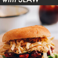 A vegan bbq tempeh sandwich with sweet and spicy slaw on a plate