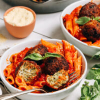 Skillet of turkey meatballs behind two bowls of pasta with meatballs