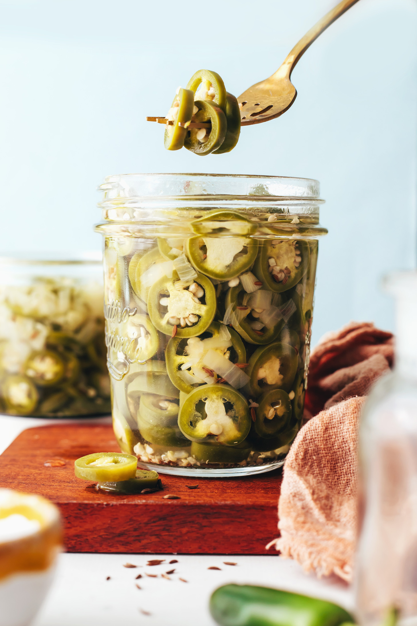 Quick pickled jalapenos on a fork over a jar with more of them