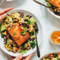 Hands holding a bowl of our smoky summer salad with lime-crusted salmon