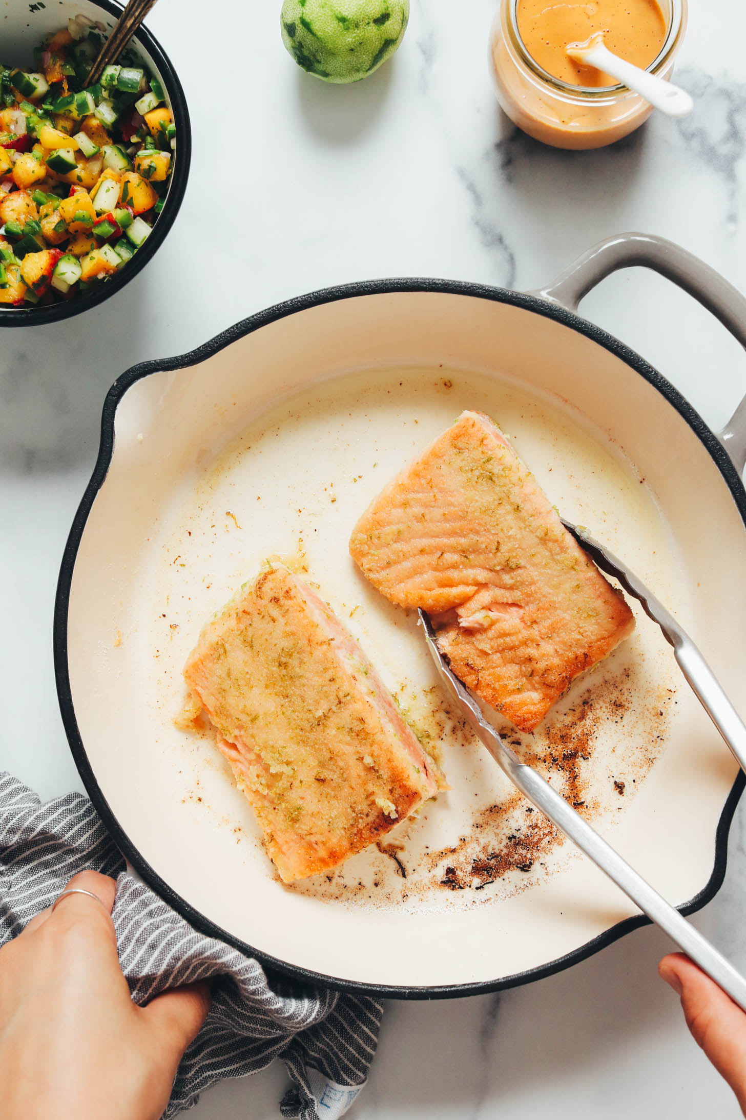 Using tongs to flip salmon filets in a skillet
