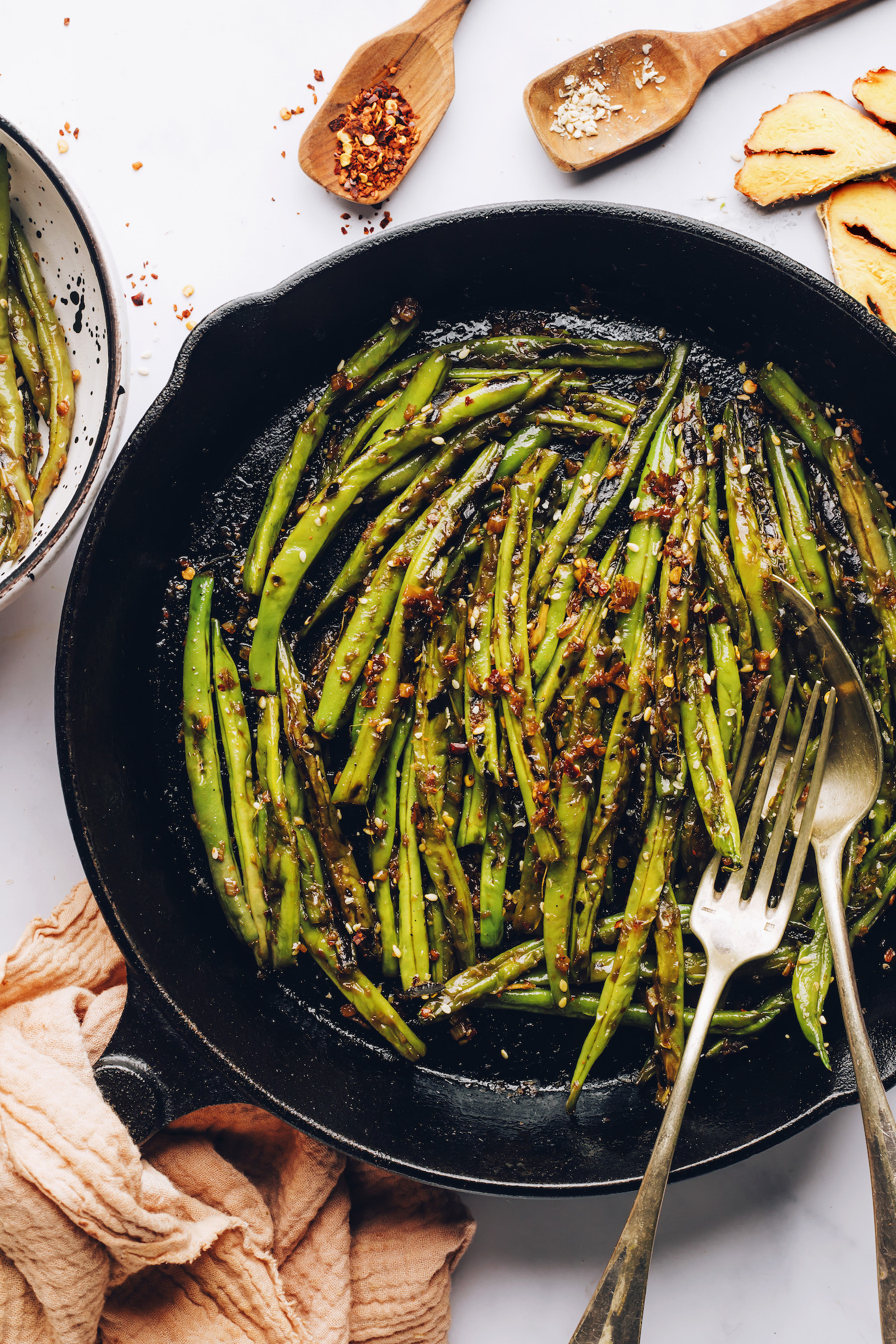 Fork and spoon in a skillet of spicy stir-fried green beans