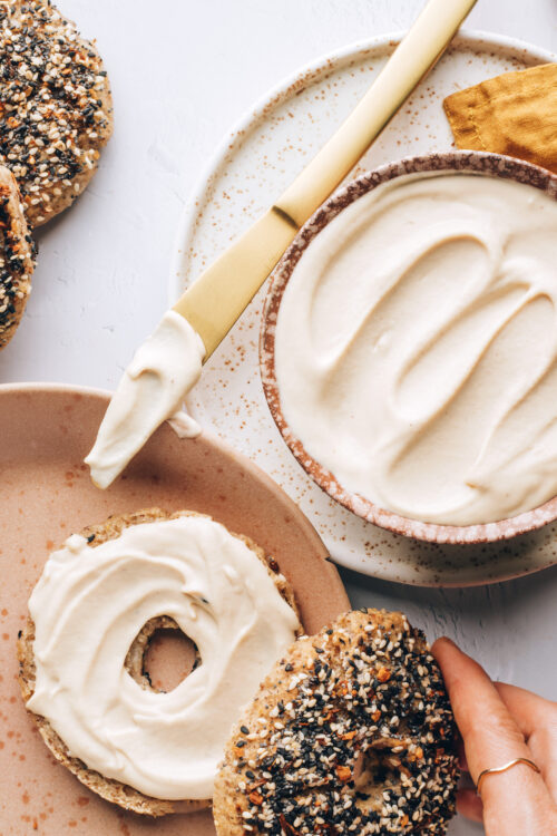 Bowl of vegan cream cheese next to a bagel