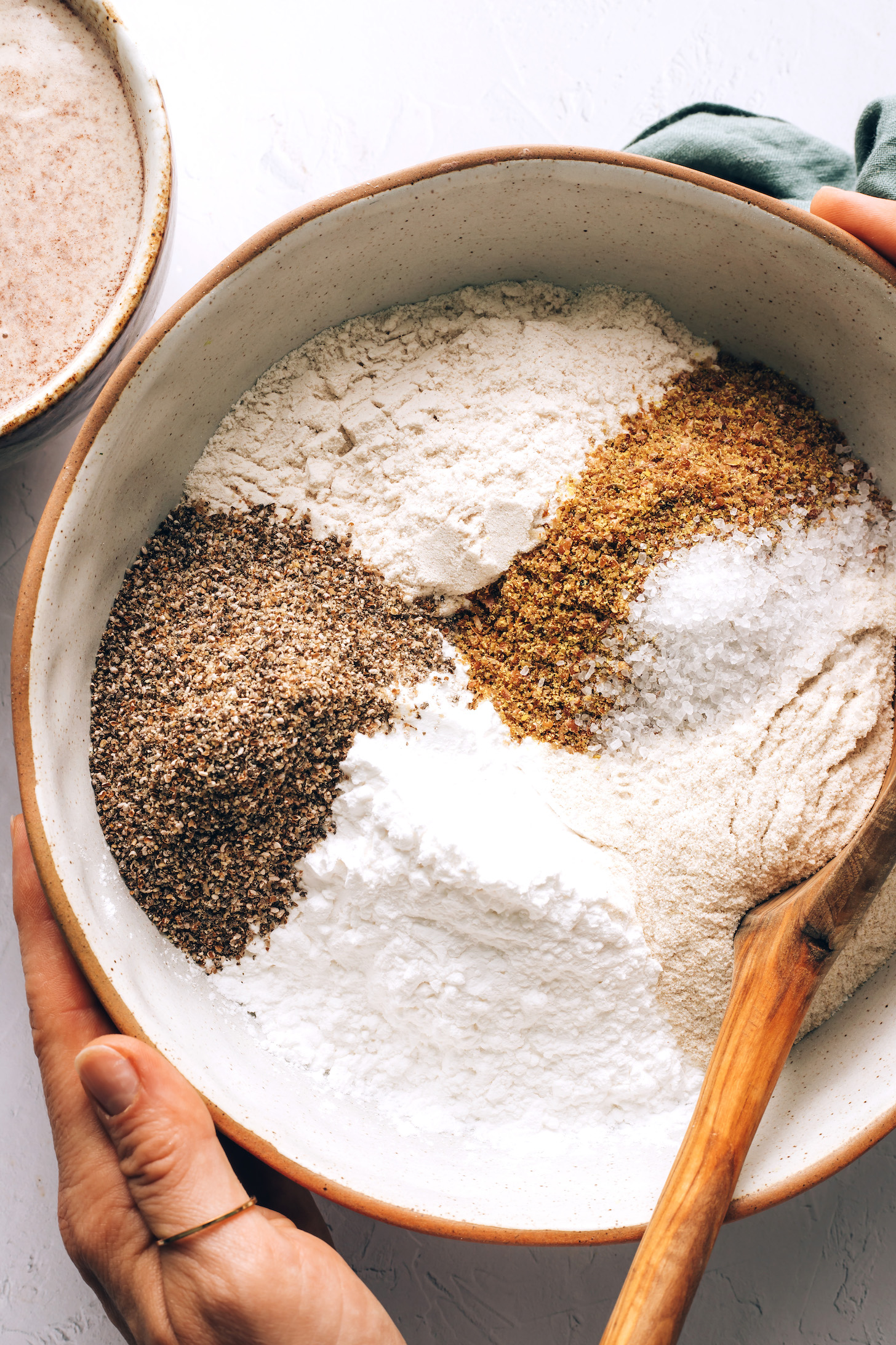 Wooden spoon in a bowl of sorghum flour, tapioca starch, brown rice flour, ground chia and flax, and sea salt