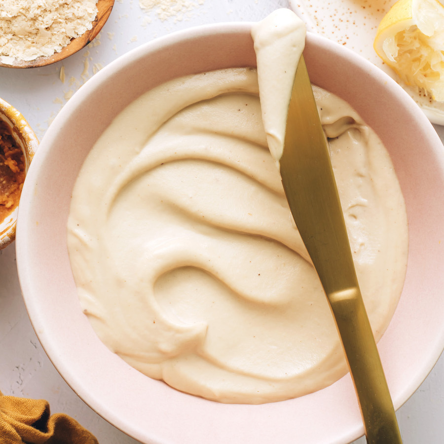 Gold knife resting on the edge of a bowl of our vegan cream cheese recipe