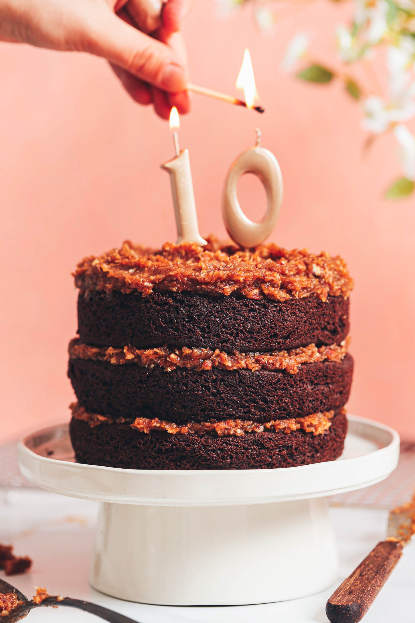 Lighting a candle on our vegan gluten-free German chocolate cake to celebrate our 10 years of blogging