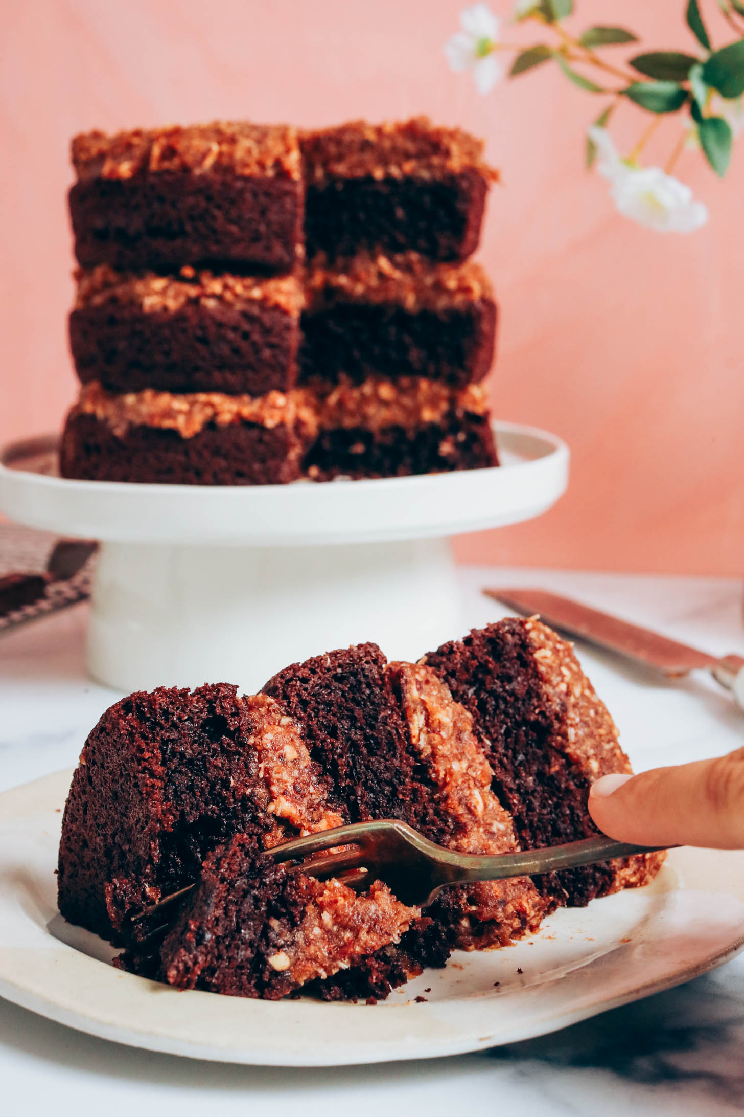 Cutting with a fork into a slice of gluten-free vegan German chocolate cake