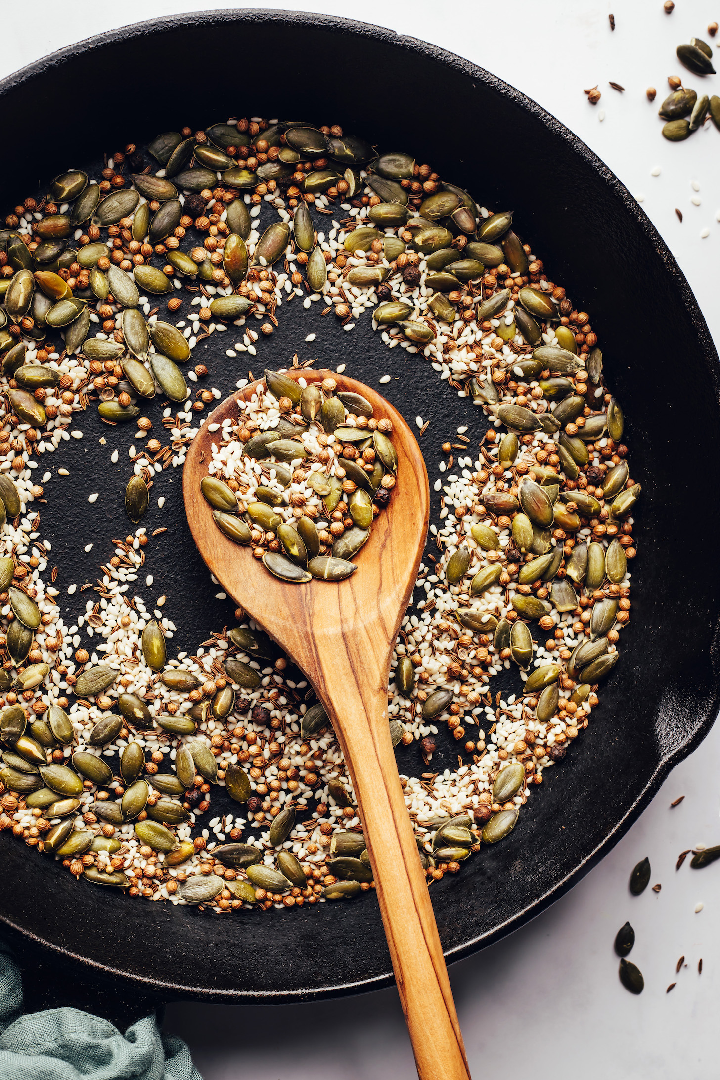 Toasted pepitas, sesame seeds, coriander seeds, cumin seeds, and black peppercorns in a skillet