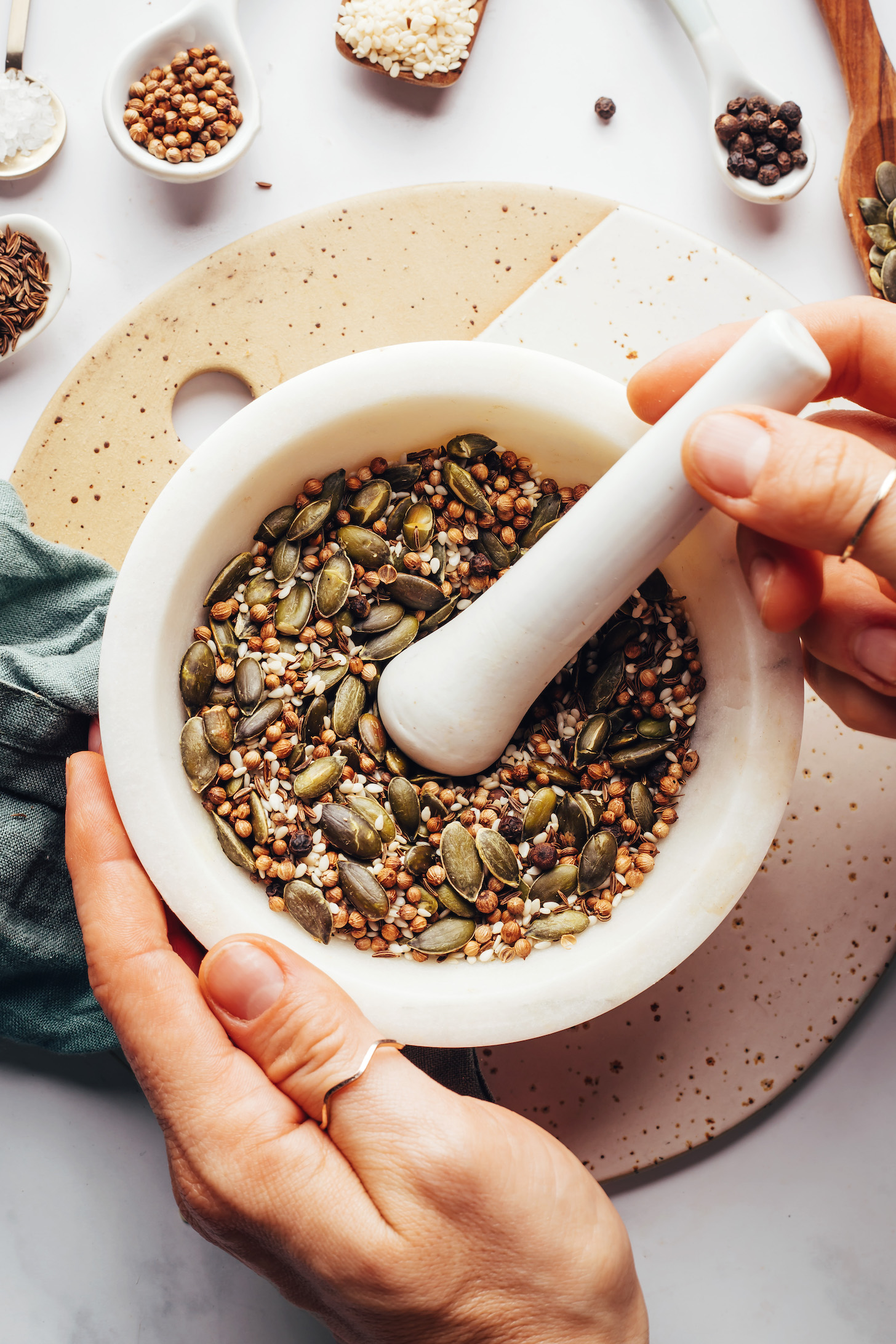 Toasted pepitas, sesame seeds, coriander seeds, cumin seeds, black peppercorns, and salt in a mortar and pestle