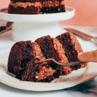 Using a fork to cut into a slice of vegan gluten-free German chocolate cake