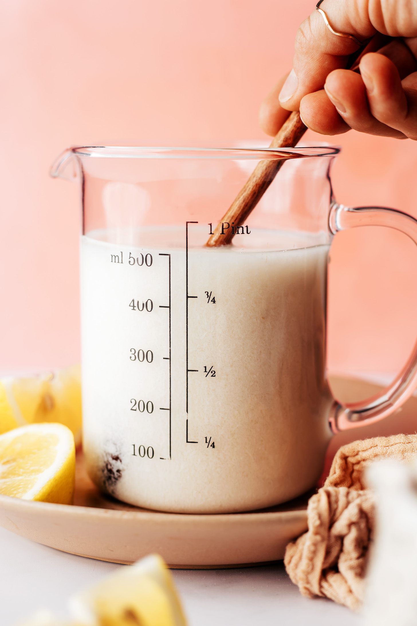 Stirring almond milk and lemon juice in a measuring glass to make vegan buttermilk