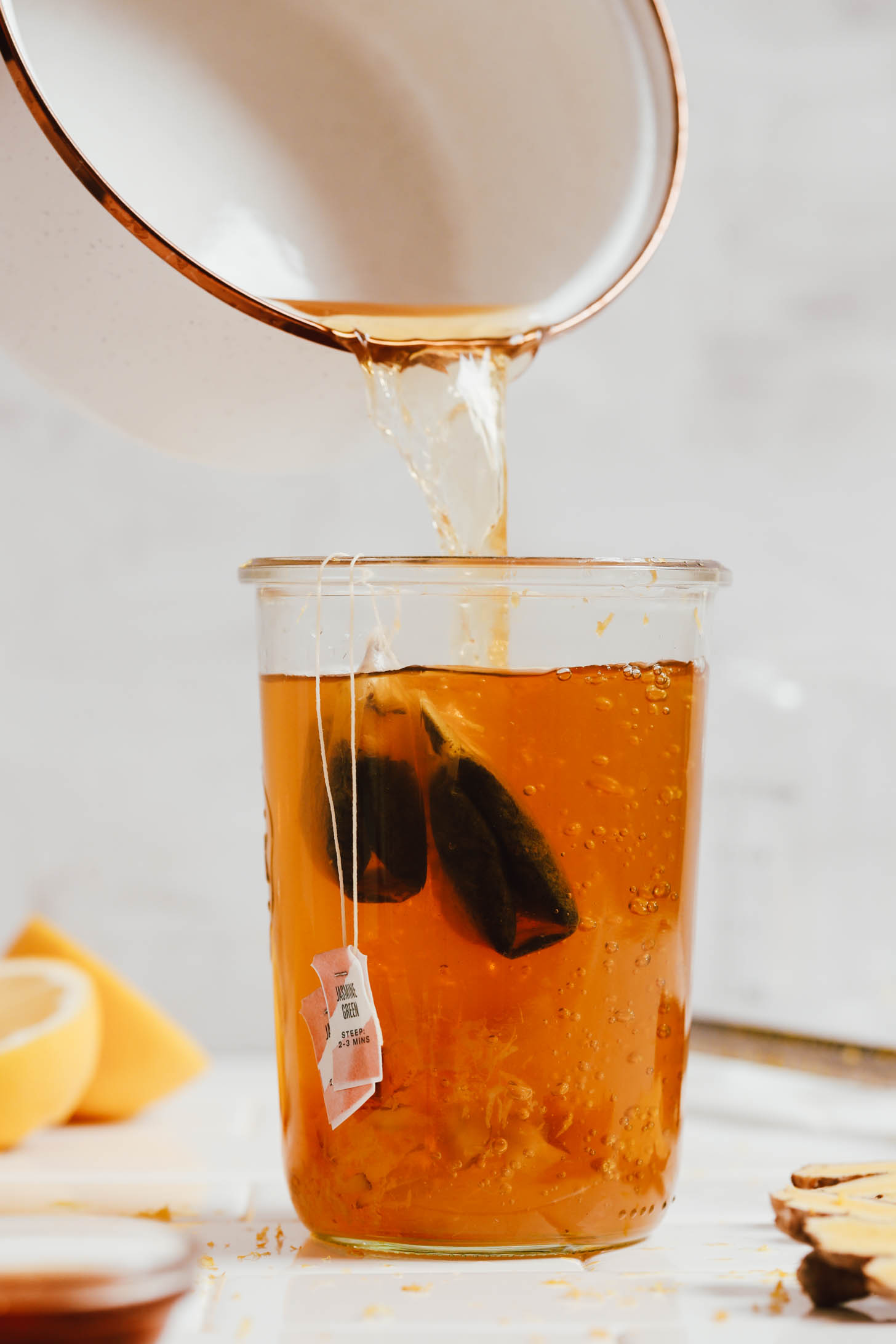 Versare il tè allo zenzero fresco in un barattolo di tè verde al gelsomino